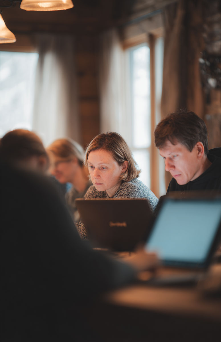 kdm-blog-header-2-0925 People working on laptops in a cozy, wood-paneled room with soft lighting.